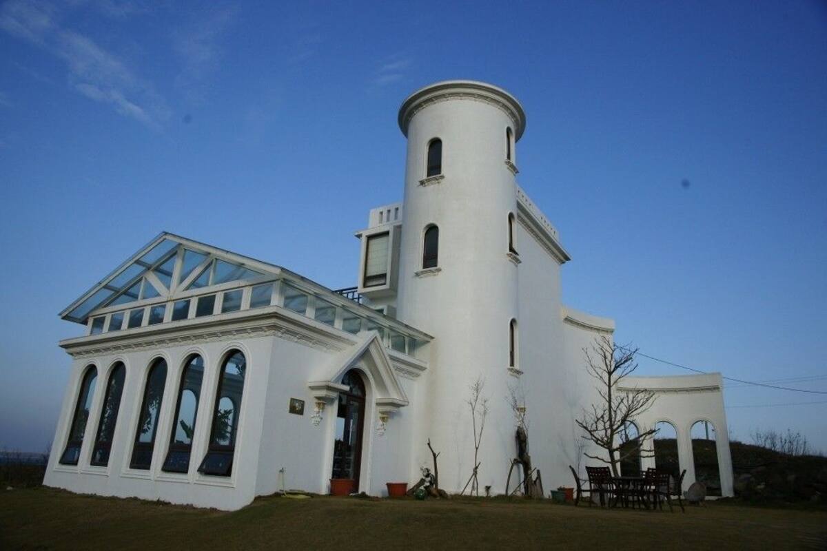 A white building with a glass roof and a cylindrical tower.