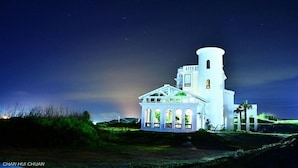 A white building with a tower and arched windows, surrounded by greenery and a clear sky. - 23.5 Blue B & B (Xiyu)