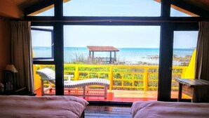 A room with two beds and a large window overlooking a beach. - 23.5 Blue B & B (Xiyu)