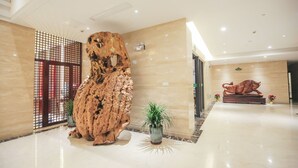 A lobby with a large wooden sculpture, a potted plant, and a bull statue. - New Knight Royal Hotel (Shanghai)