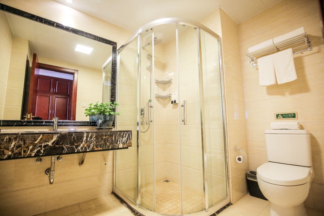 A modern bathroom with a glass-enclosed shower, a marble sink, and a toilet.