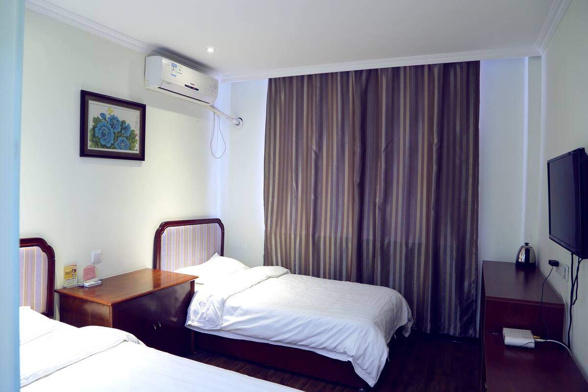 Une chambre d’hôtel avec deux lits, un bureau, une télévision et un appareil de climatisation.