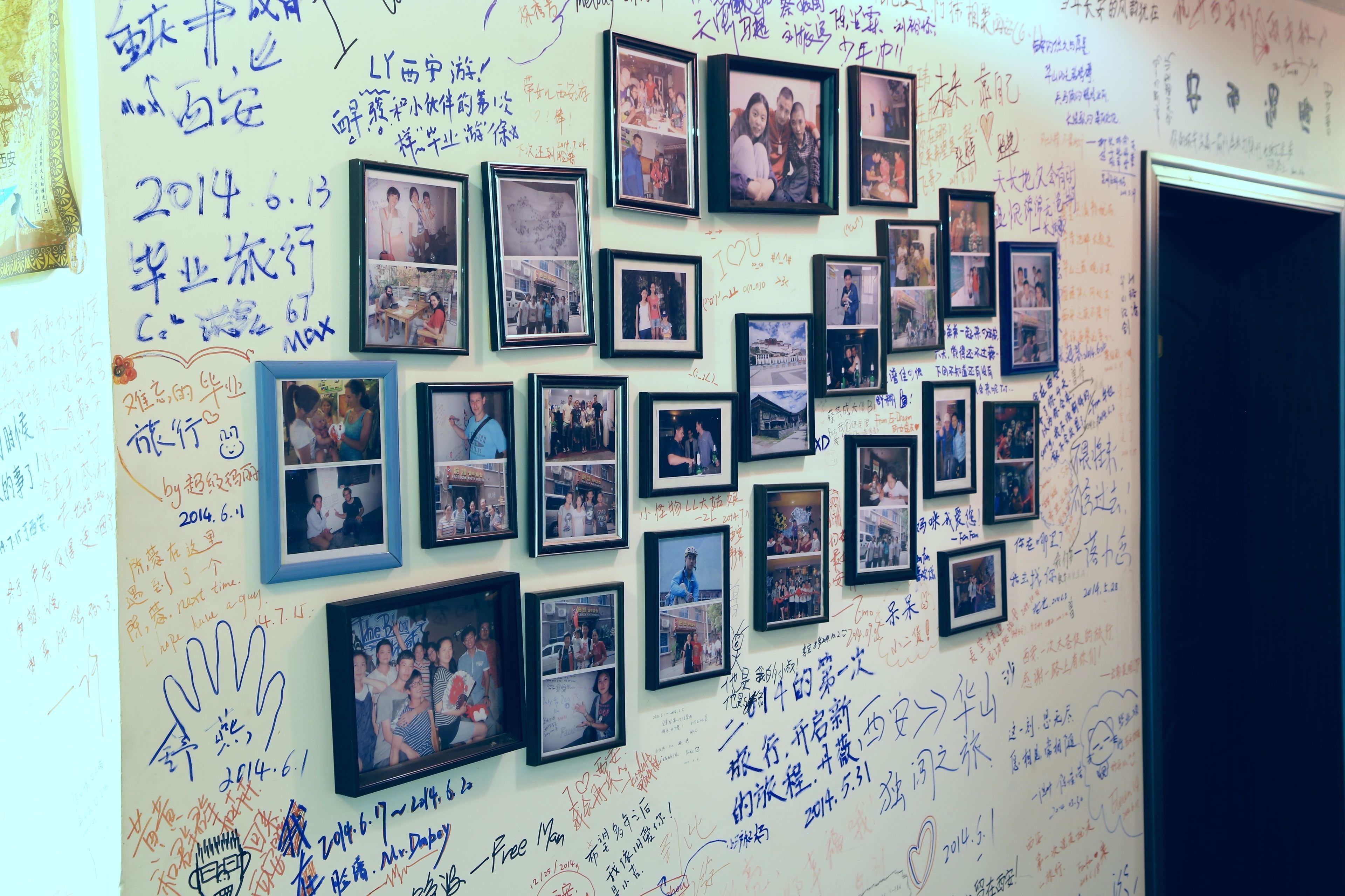 Eine Wand mit mehreren gerahmten Fotos und handgeschriebenen Notizen.