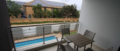 Un balcón con piscina, una mesa y sillas.