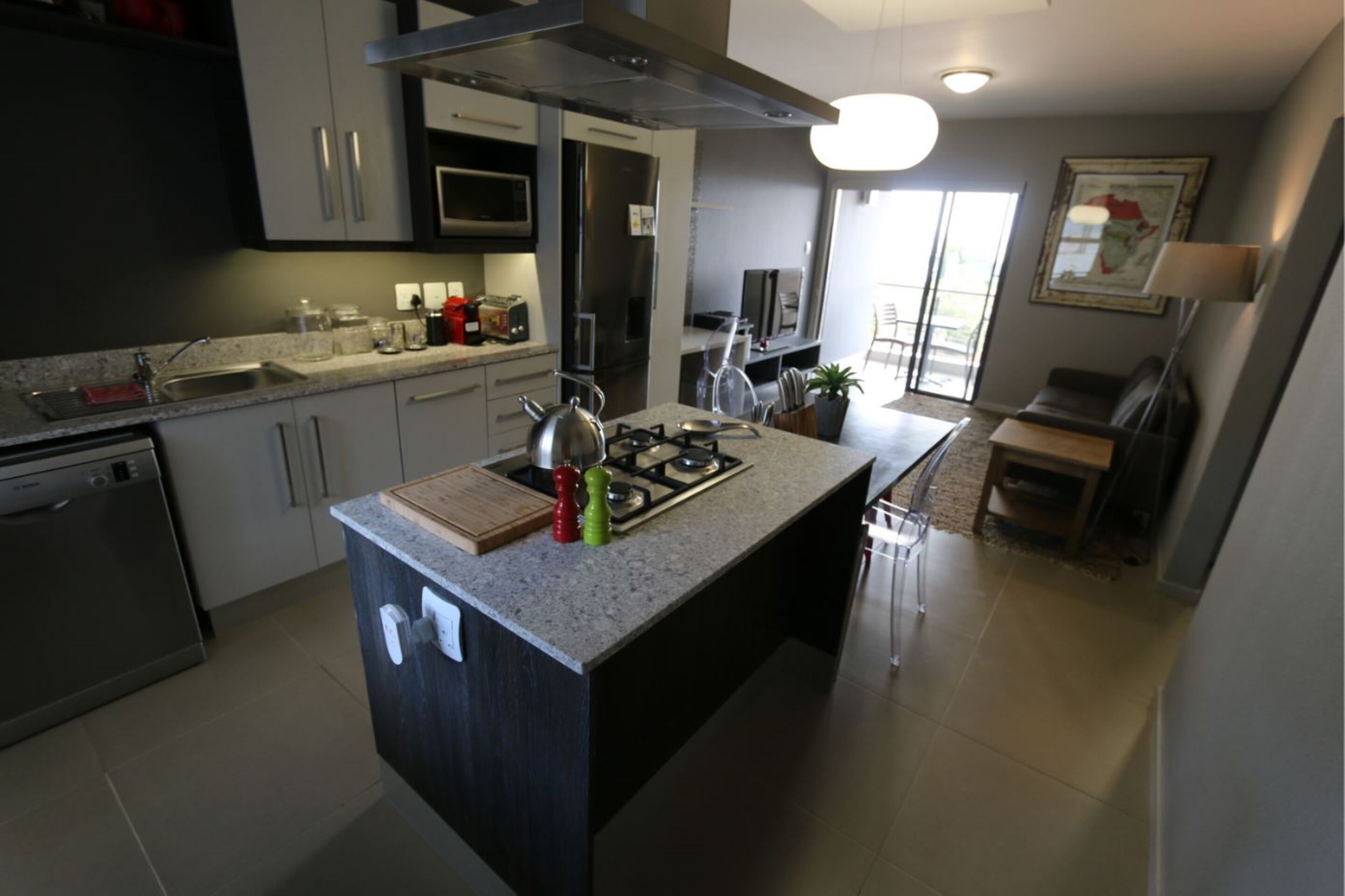 A modern kitchen with stainless steel appliances, a central island, and a dining area with a view.