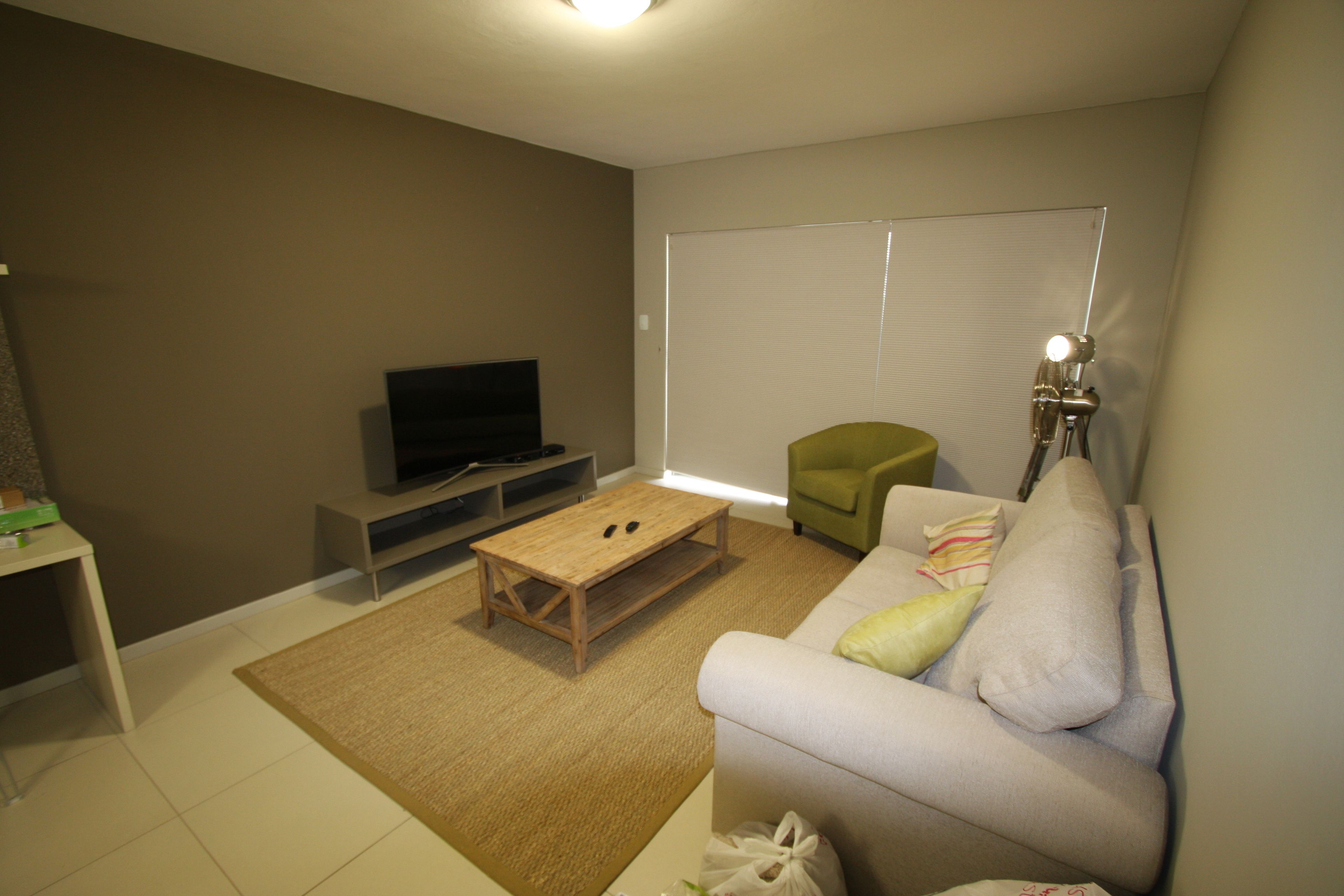 Ein Wohnzimmer mit einer Couch, einem Couchtisch, einem Fernseher und einer Lampe.