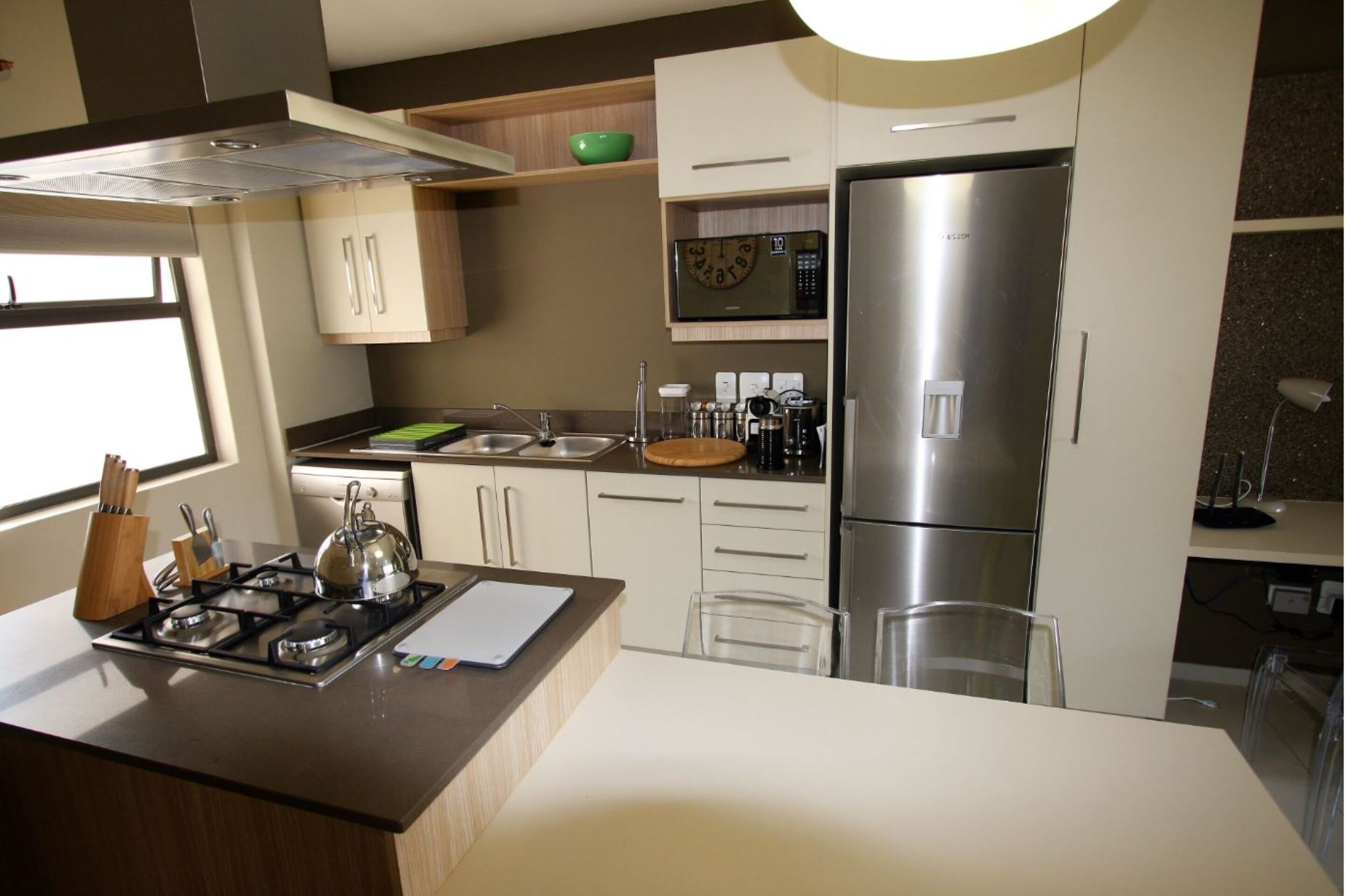 A modern kitchen with a gas stove, microwave, refrigerator, and white cabinetry.