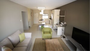 A modern living room with a sofa, a coffee table, a TV, and a dining area with a table and chairs.