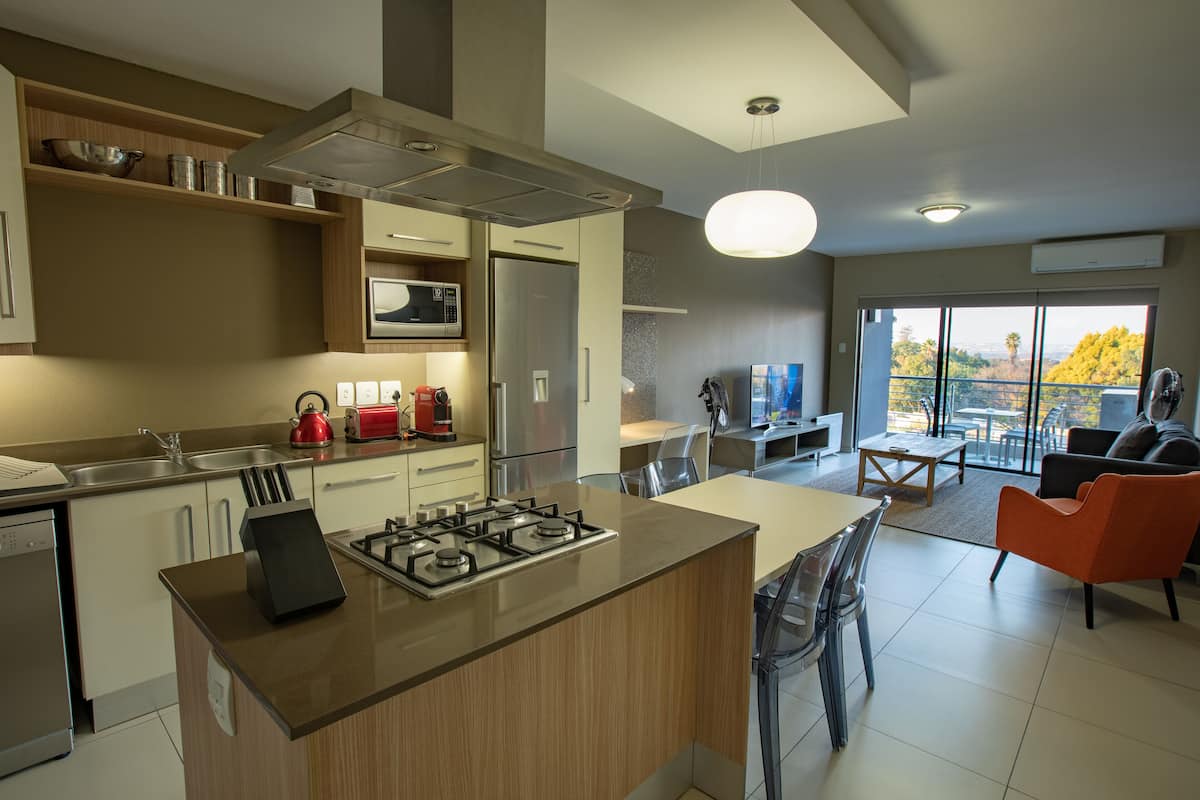 A modern kitchen with a central island, stainless steel appliances, and a dining area with a view.