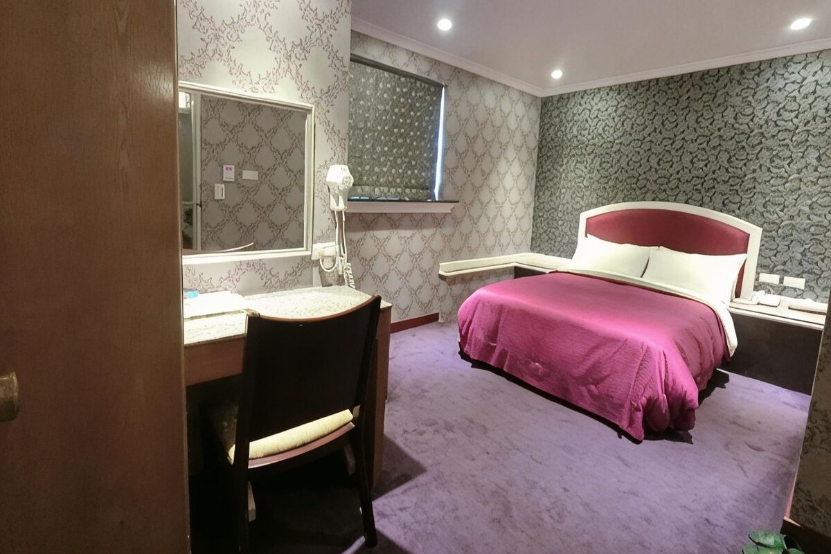A bedroom with a bed, a desk, and a chair.