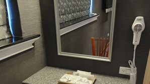 A small bathroom with a mirror, a hairdryer, and a tray with toiletries. - Nice Hotel (Taipei)
