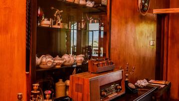 Een houten interieur met een grote spiegel, planken met decoratieve objecten, en een vintage radio.