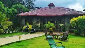 A building with a red-tiled roof, surrounded by lush greenery and a well-maintained lawn. - MF Estate Holiday Bungalow (Hali-Ela)