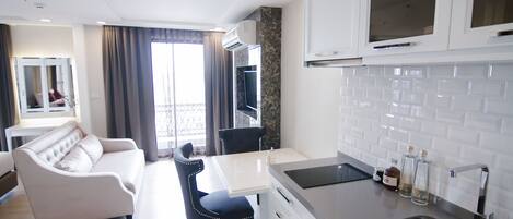 Una cocina moderna con armarios blancos, un lavamanos de acero inoxidable y un comedor con mesa blanca y sillas azules.