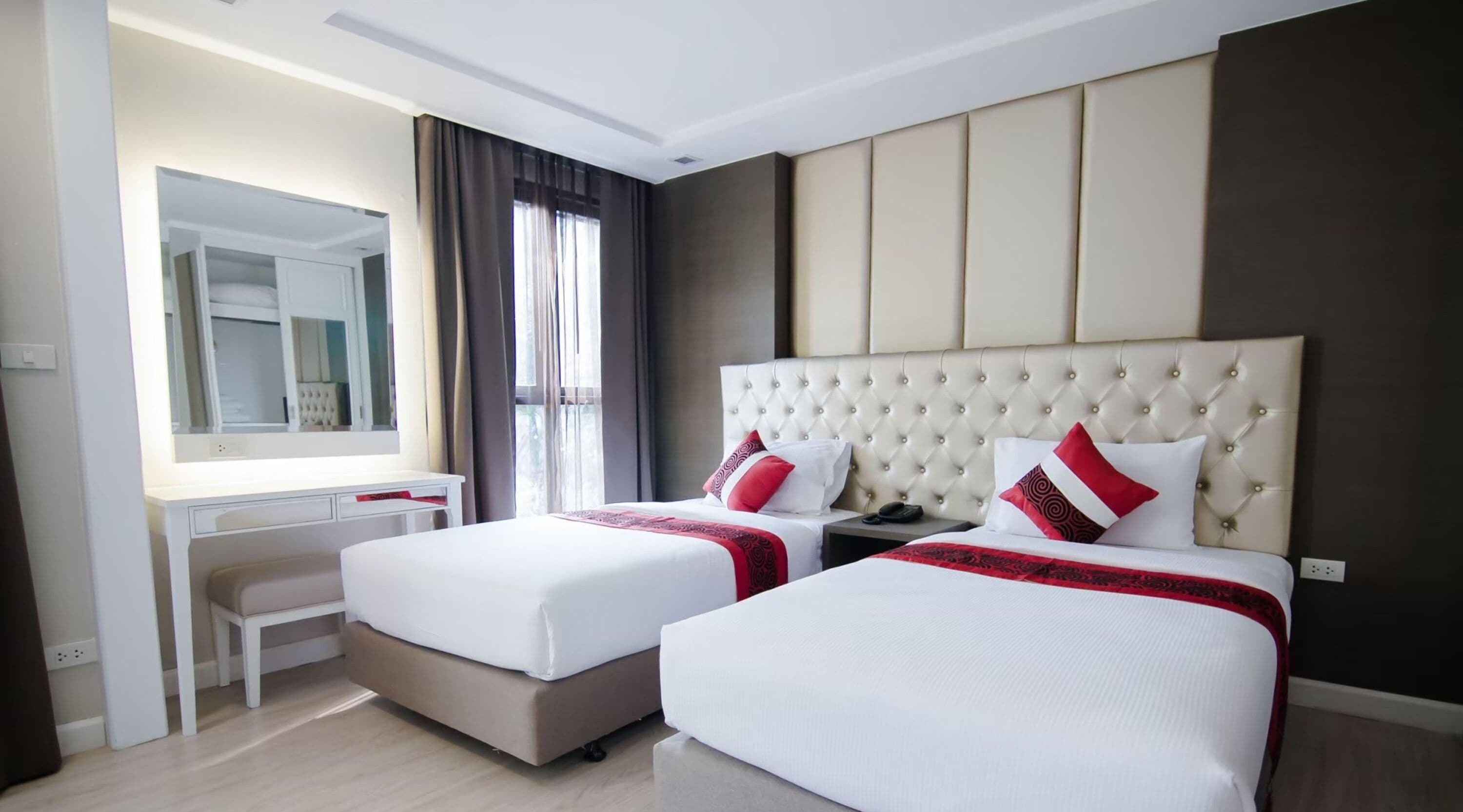 Ein Hotelzimmer mit zwei Betten, einem Schreibtisch und einem großen Spiegel.