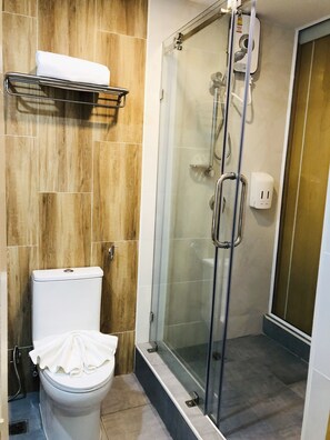 A modern bathroom with a toilet, a glass shower enclosure, and a wooden wall.