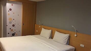 Habitación de hotel con cama, dos mesitas de noche, un armario y una pared con diseño geométrico.
