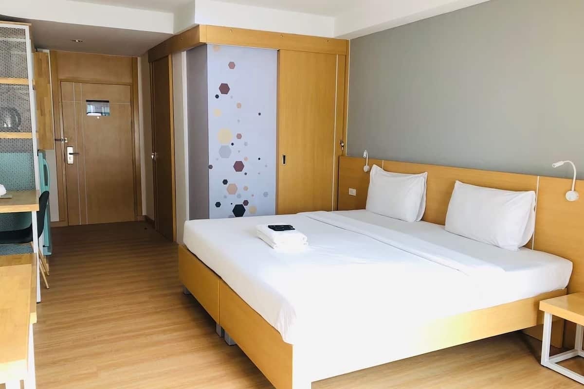 A hotel room with a large bed, a desk, and a wardrobe.