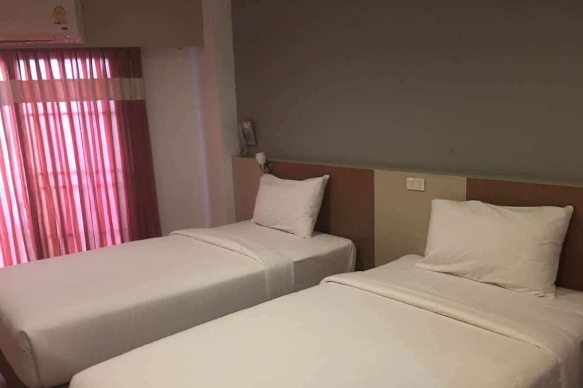 Two single beds with white linens in a hotel room.
