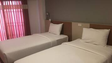 Dos camas individuales con ropa blanca en una habitación de hotel.