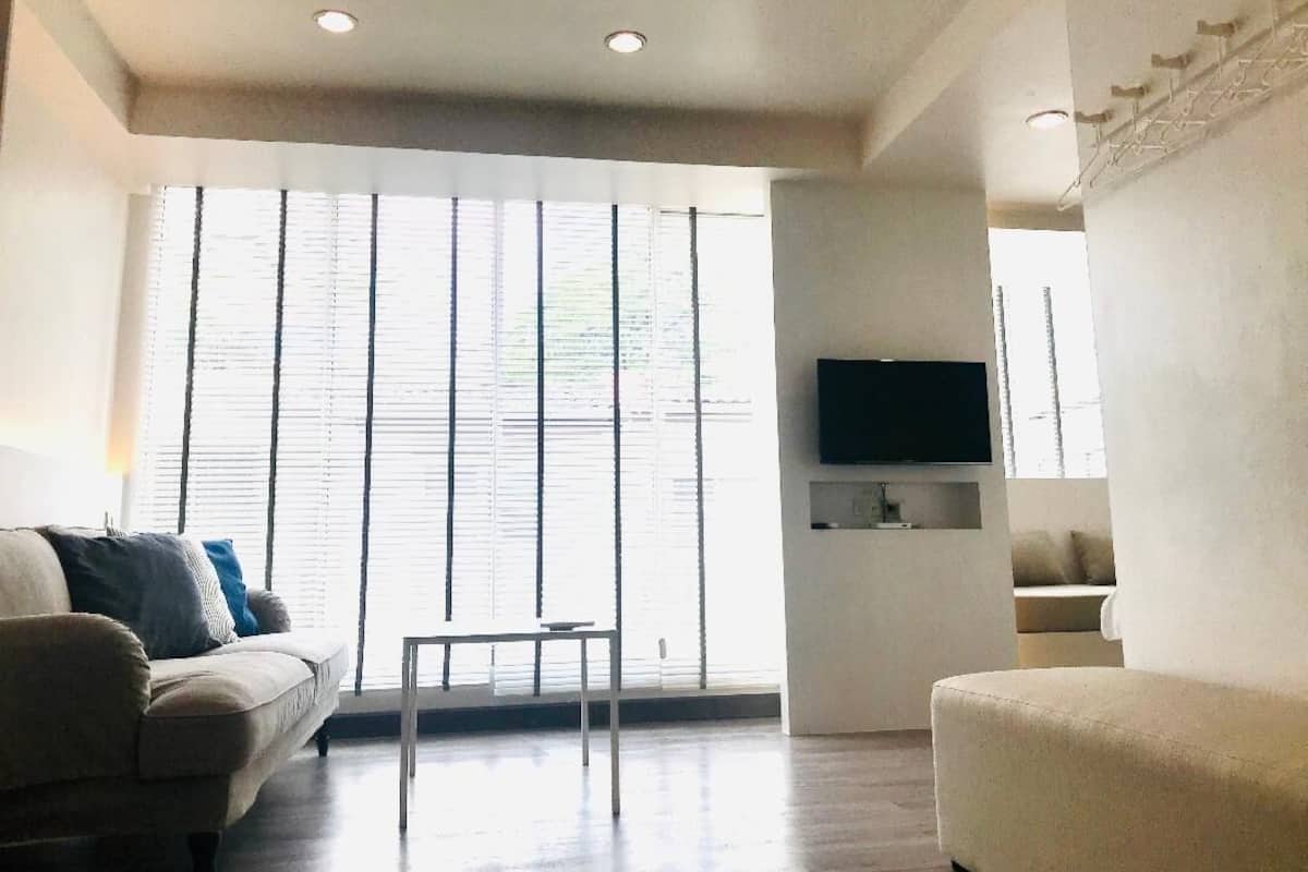 A living room with a sofa, a coffee table, and a TV mounted on the wall.