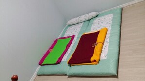 A neatly made bed with a green and white quilt, two pillows, and a folded blanket. - MK Guest House (Busan)