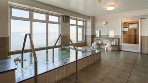 Ein Wellnessbereich mit großem Fenster, Pool und Duschbereich.
