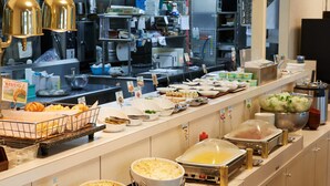 Ein Buffet mit verschiedenen Speisen und Geschirr, darunter Schüsseln, Tellern und eine Zange zum Servieren.