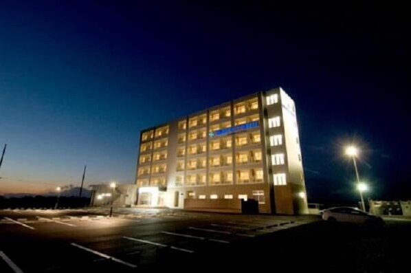 A multi-story building with illuminated windows at night, a parking lot, and a streetlight.
