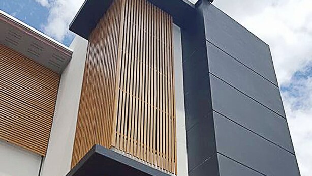 A modern building with a combination of wooden slats and dark panels on the facade.