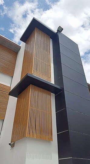 Un edificio moderno con un rivestimento che combina listelli di legno e pannelli scuri.