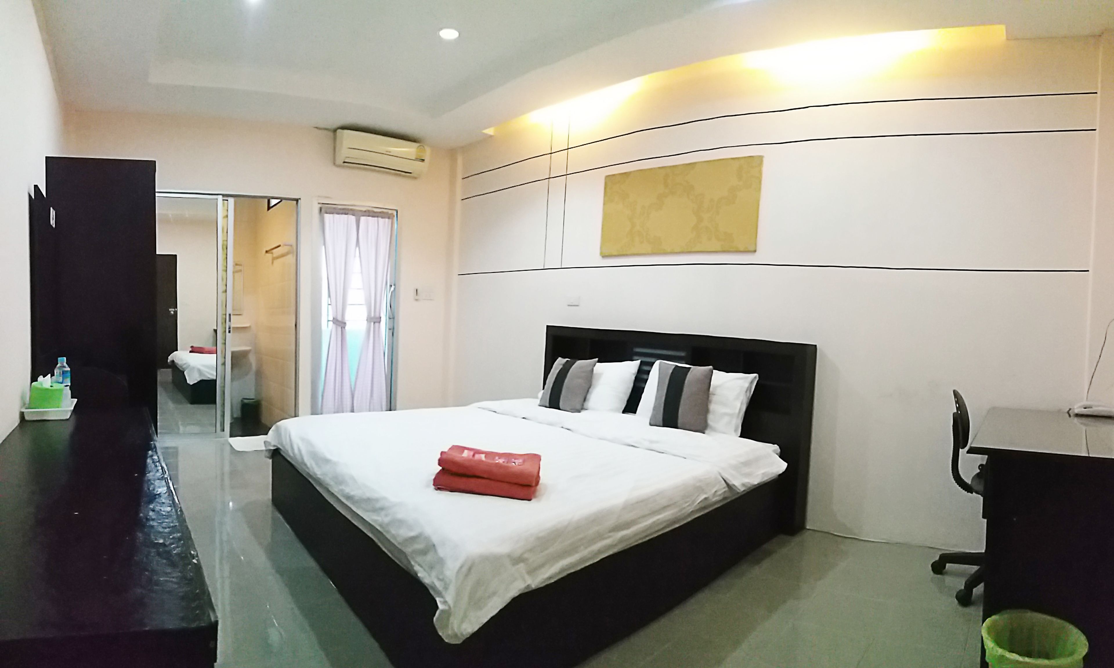 A hotel room with a bed, bedside table, and a small desk.