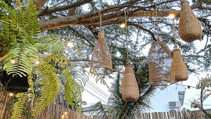 An outdoor dining area with bamboo walls, hanging baskets, and a variety of dishes on the table.
