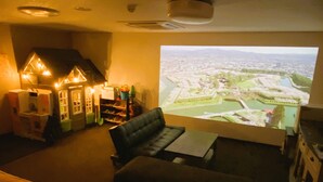 A cozy room with a large window displaying a cityscape. There is a comfortable couch and a small table. - A-Gate Hotel (Hakodate)