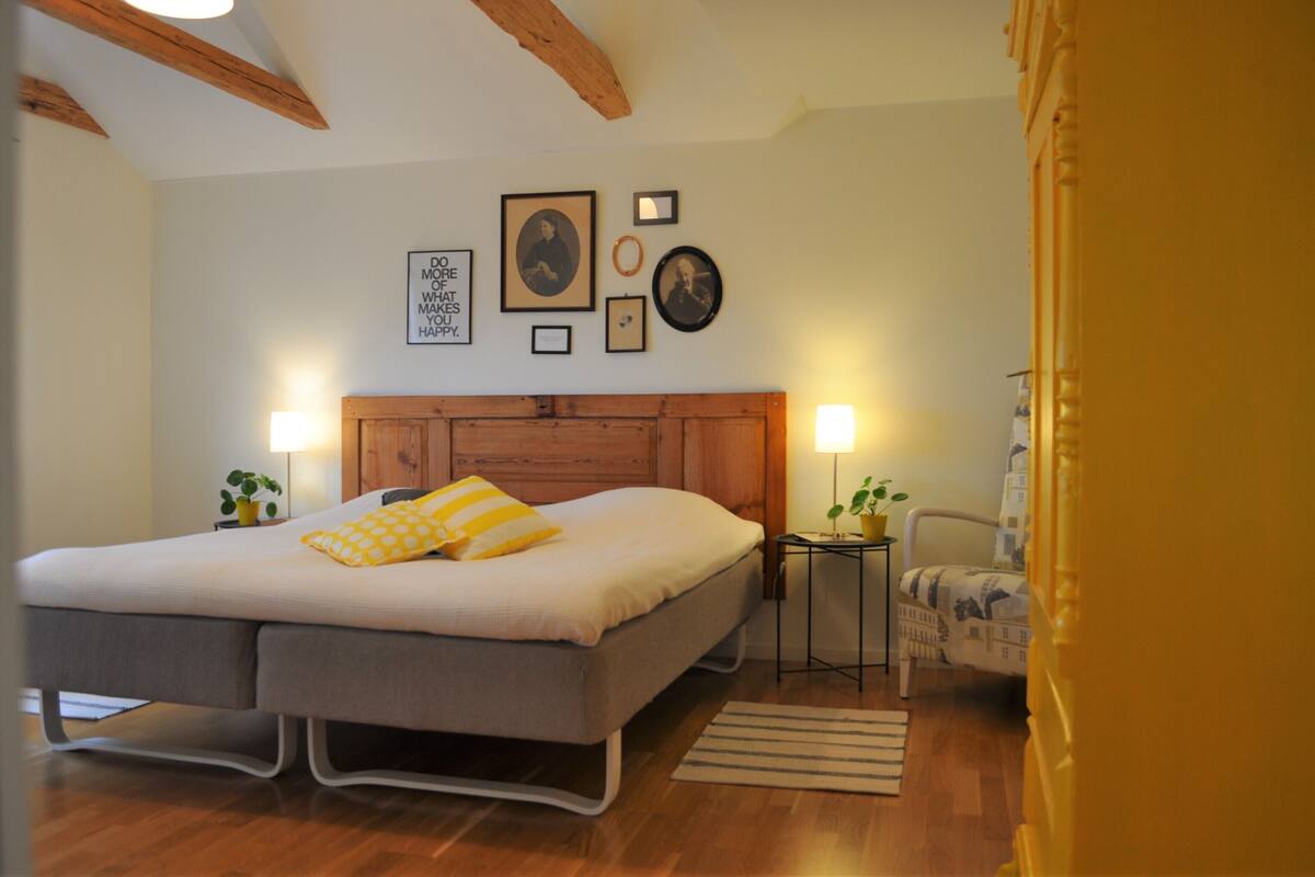 A bedroom with a bed, bedside tables, a chair, and wall decorations.