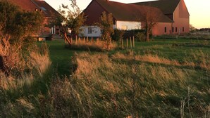 A rural landscape with a large barn and a white house with a red roof. - Villa Sandby Bed and Breakfast (Borrby)