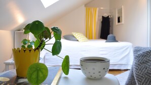 A cozy bedroom with a bed, a bedside table with a cup and a plant, and a window with curtains. - Villa Sandby Bed and Breakfast (Borrby)