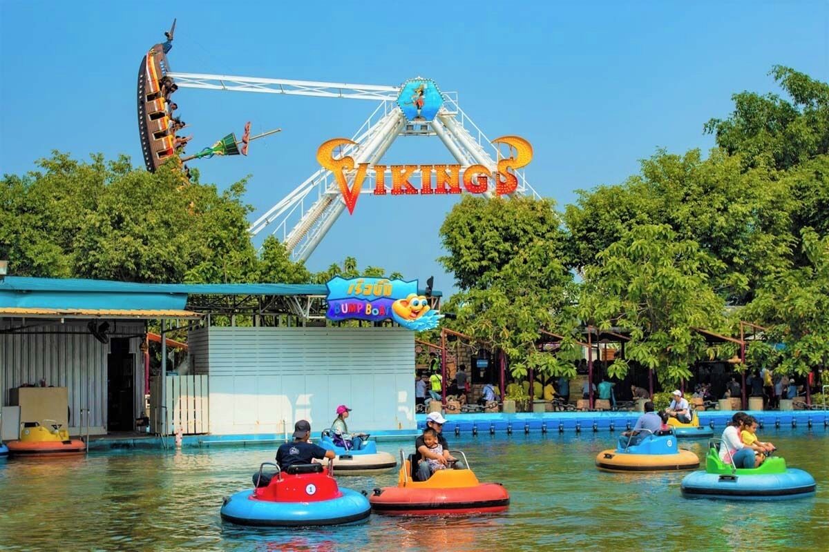 A water ride with colorful bumper cars and a Viking-themed Ferris wheel in the background.
