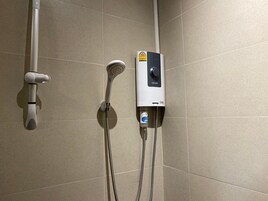 Ducha con cabezal de ducha de mano y panel de control en la pared.