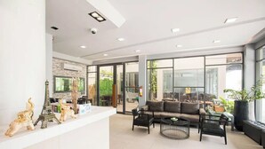 A modern reception area with a white reception desk, a sofa, a coffee table, and decorative items including a model of the Eiffel Tower. - Tara Park Resotel (Thanyaburi)