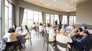 A conference room with multiple tables and chairs, large windows, and a modern ceiling design. - Tara Park Resotel (Thanyaburi)