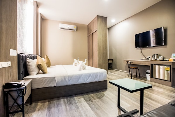 A modern hotel room with a bed, a desk, a TV, and a kitchenette. - Tara Park Resotel (Thanyaburi)