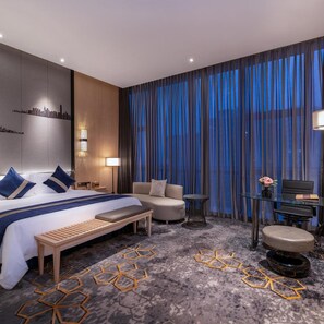 A modern hotel room with a bed, a sofa, a desk, and a chair.