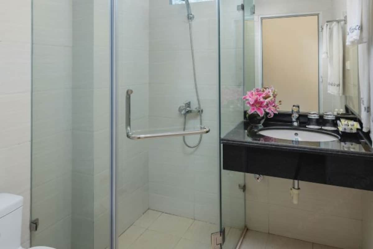 A modern bathroom with a glass shower enclosure, a black sink vanity, and a mirror.