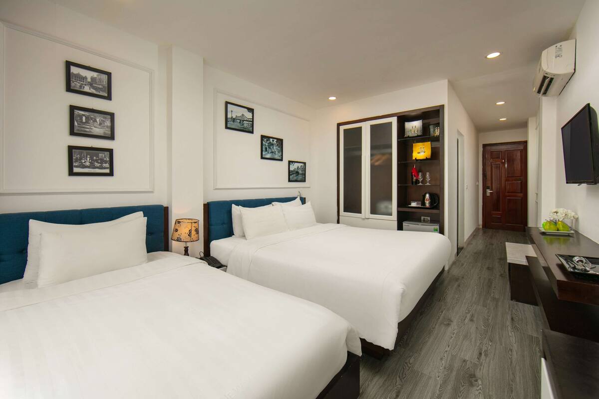 Habitación de hotel con dos camas, un escritorio, un armario y un televisor.