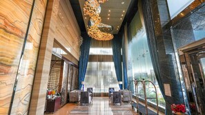 A modern hotel lobby with marble walls, a chandelier, seating area, and large windows. - Boudl Al Sahafa (Riyadh)
