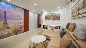 A modern living room with a sofa, a round table, and a painting of a cityscape. - Gia Hoa Hotel (Ho Chi Minh City)