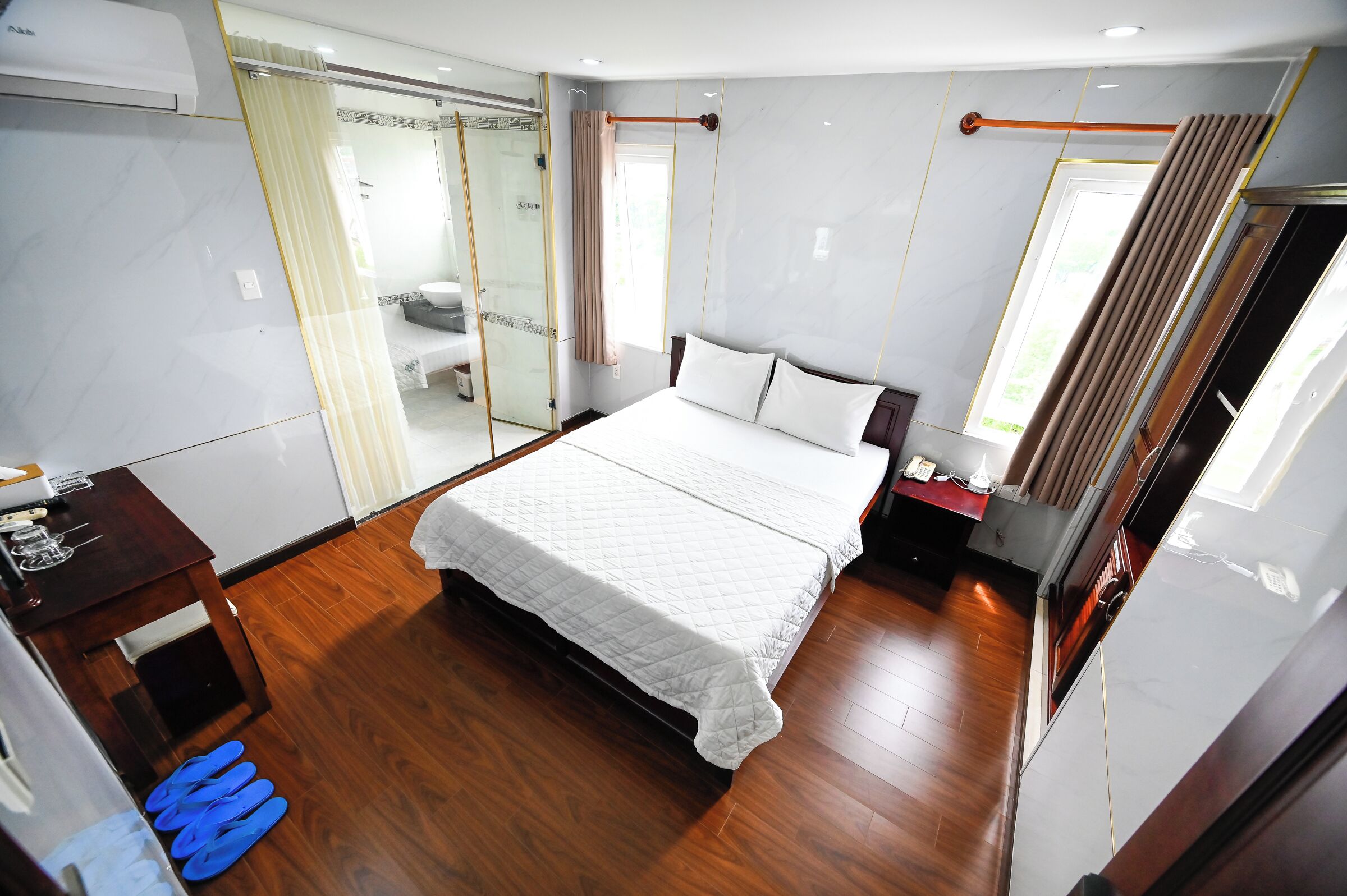 Une chambre d’hôtel moderne dotée d’un grand lit, d’un bureau avec une chaise, d’une petite table et d’une cabine de douche en verre.