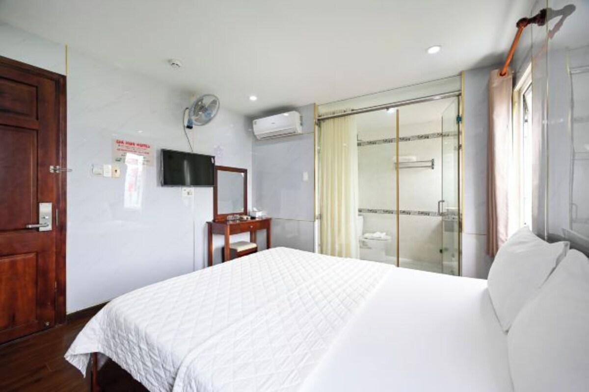 Une chambre d’hôtel équipée d’un lit, d’un bureau, d’un miroir, d’une télévision, d’un climatiseur et d’une douche en verre.