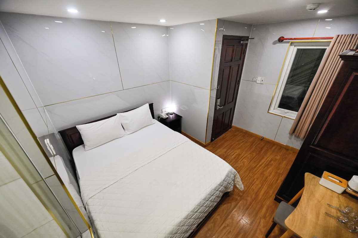 Une chambre d’hôtel avec un lit, une table de chevet et une petite table en bois avec une chaise.